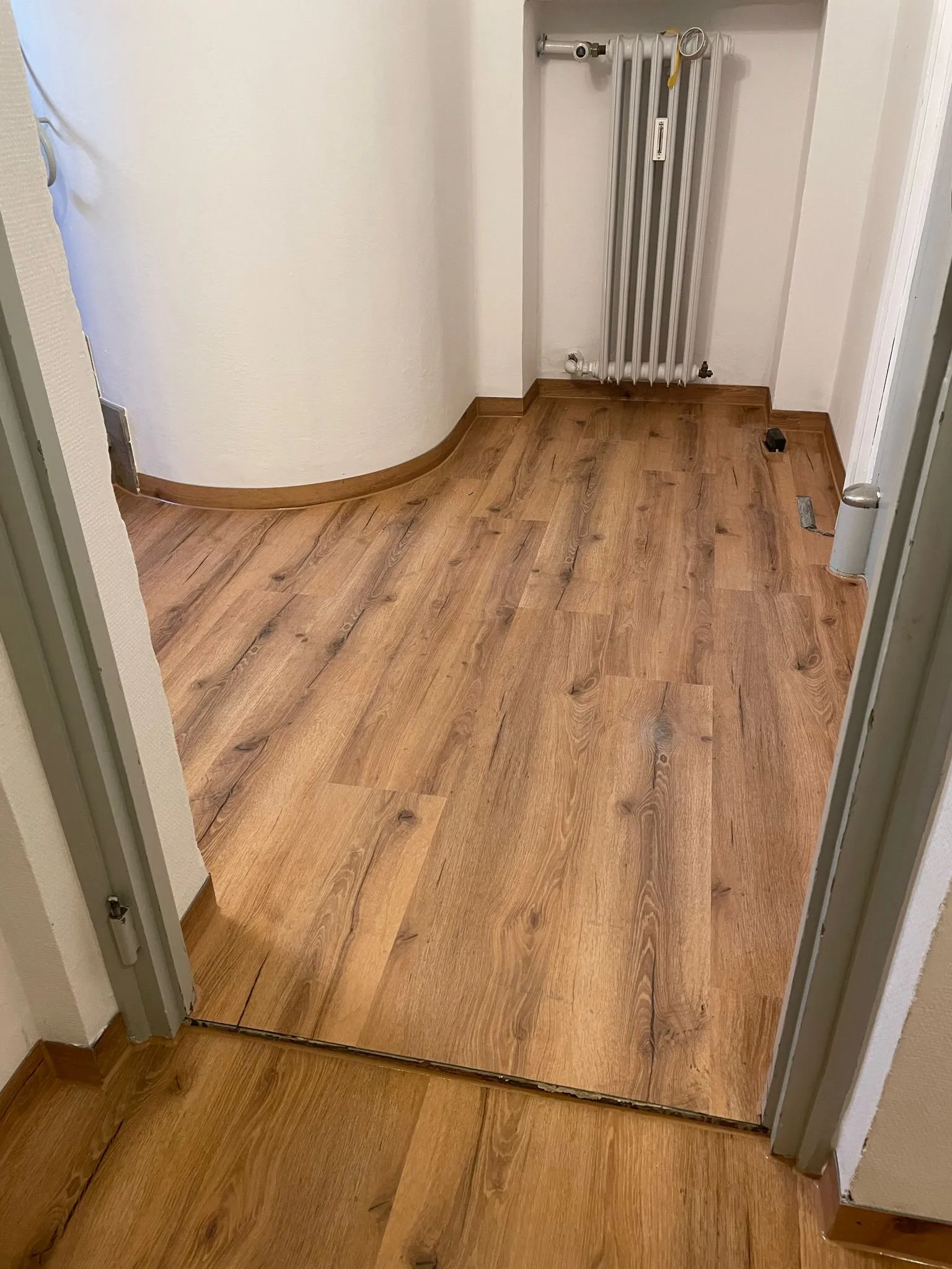 Laminat um eine Rundwand verlegt, mit passend gebogener Sockelleiste