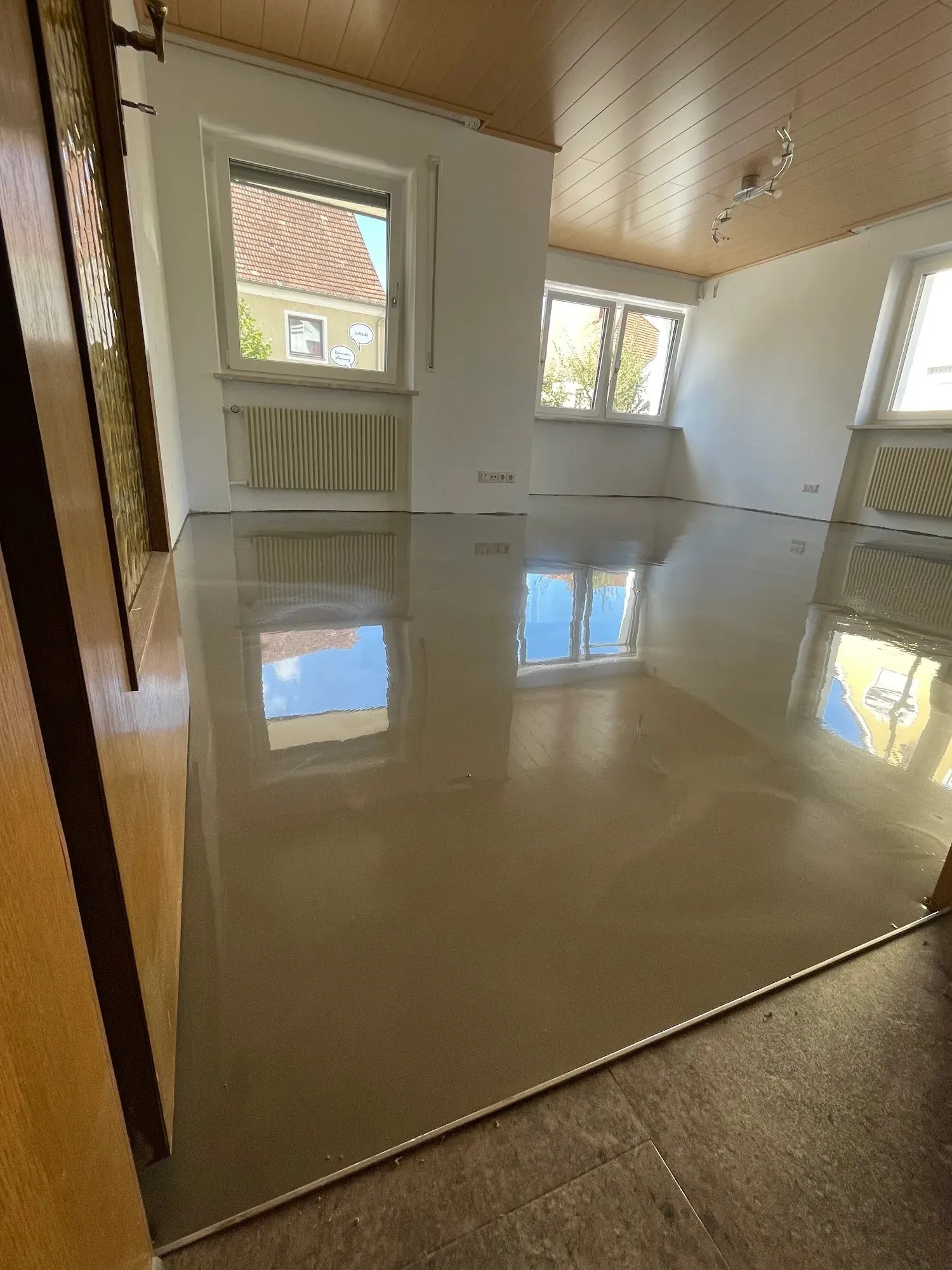 Frisch gegossene Spachtelmasse, spiegelglatt — sie reflektiert Fenster und Himmel